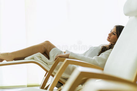 美丽的女人穿着长袍躺在椅子上放松