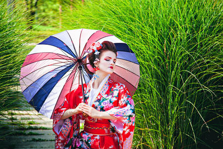 穿着艺妓服装的女孩带着雨伞