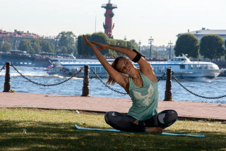 美丽的女孩穿着适合运动的衣服和耳机，在圣彼得堡的海滨做健身或瑜伽。