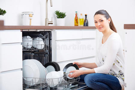 20多岁的女人在厨房里，清空洗碗机