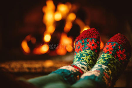 穿着羊毛袜子的脚在壁炉边。 女人通过温暖的FI放松