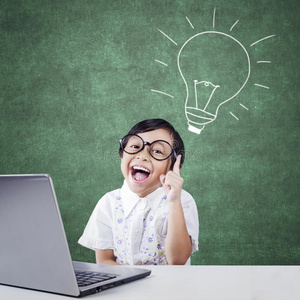 聪明的小孩带着笔记本电脑和灯照片