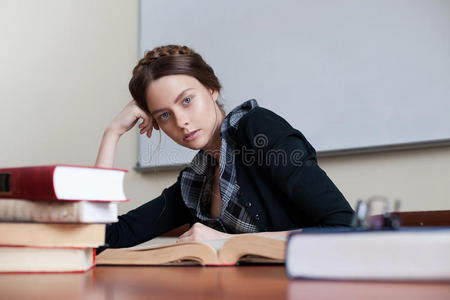 漂亮的女学生在一张桌子上拿着书