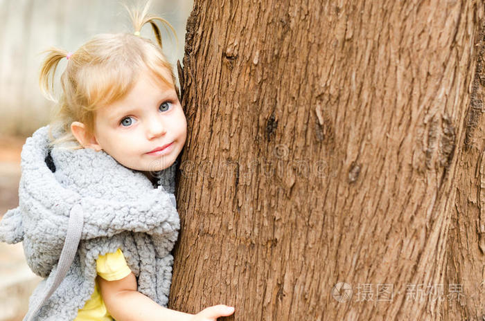 可爱的小女孩拥抱公园里的树