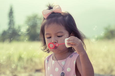 孩子可爱的小女孩在公园里吹肥皂泡