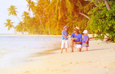 父亲和两个孩子在海滩上收集贝壳