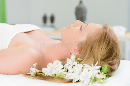 美丽的女人裹着毛巾，躺在水疗中心，白色的水流