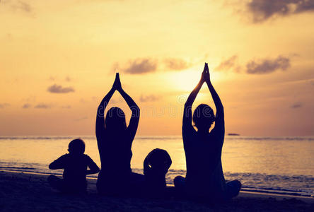 家庭剪影在日落时做瑜伽