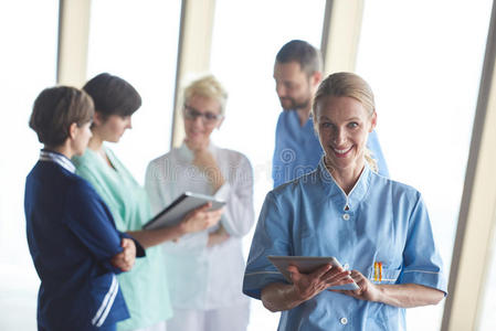 女性医生，平板电脑站在团队前面