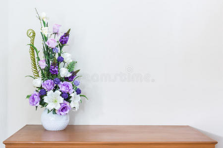 木制桌子和白色墙壁上的人造花瓶