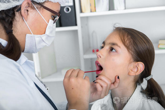 医生检查了小女孩的喉咙.色调的图像。