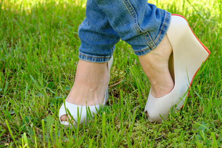 高跟鞋脚女脚穿鞋,楔形高跟鞋在绿色的草地上照片