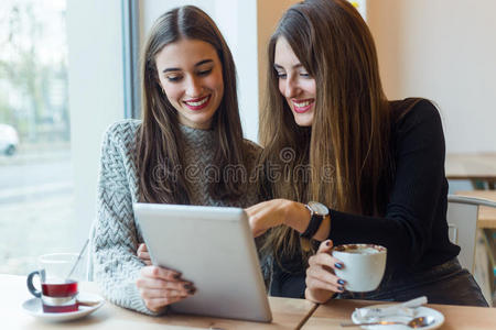 漂亮的年轻女性在咖啡店里使用数字平板电脑。
