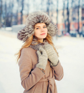 美丽快乐的微笑的女人穿着外套和帽子在冬天的雪上