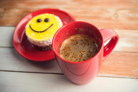咖啡红杯和木桌上的微笑蛋糕