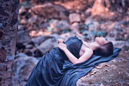 亚洲女人穿着黑色长裙躺在石头上