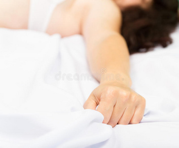 女性的手在狂喜中拉着白色的床单