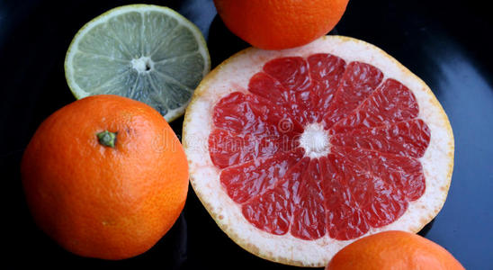 黑色光滑盘子上的各种柑橘类水果