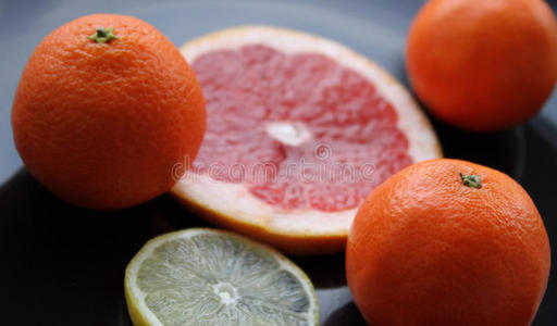 黑色光滑盘子上的各种柑橘类水果