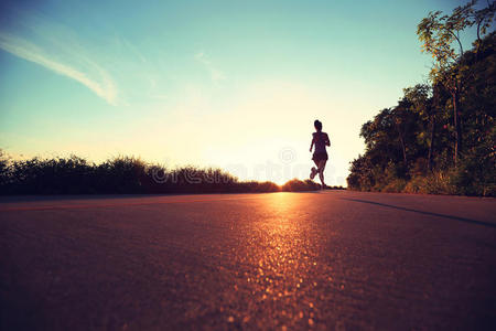 健身妇女在日出海滨小径上跑步照片