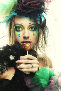 有创意化妆的女孩拿着棒棒糖。