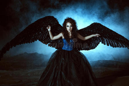 黑翅膀天使两个女孩穿着天使和魔鬼的衣服坐着倒下的黑色天使带着翅膀