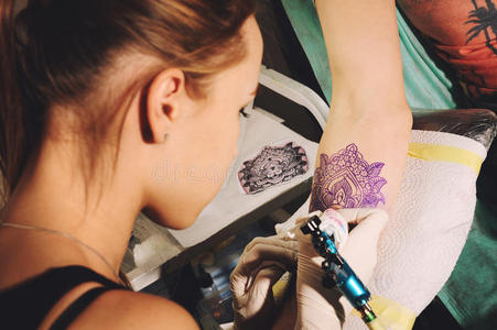 女孩纹身艺术家用素描在一只手上做纹身，以对抗未来纹身的蓝色肖像。
