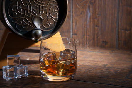 一杯威士忌加冰，放在木背上的桶旁边