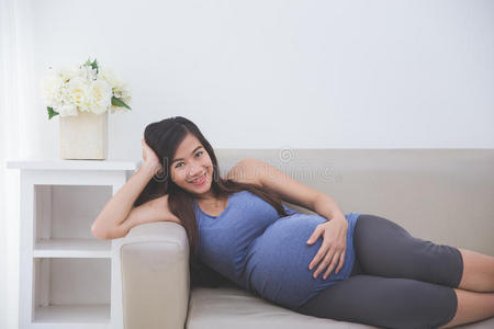 美丽的亚洲孕妇躺在沙发上