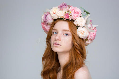 美丽的玫瑰花圈中迷人的年轻红头发女性的特写
