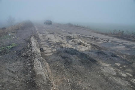 雾中坑坑洼洼的沥青道路损坏