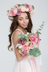 迷人的新娘戴着玫瑰花环，看着花束