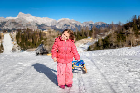 女孩穿着冬装在滑雪场拉雪橇