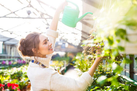 欢快的女园丁用浇水罐浇花快乐的孩子正在浇花夏天,顽皮的女孩在花园