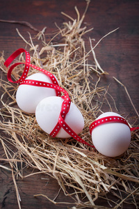 干草上有红色丝带的鸡蛋作为复活节