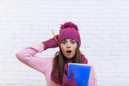 迷人的震惊少女戴着粉红色帽子的学生震惊地拿着文件夹铅笔