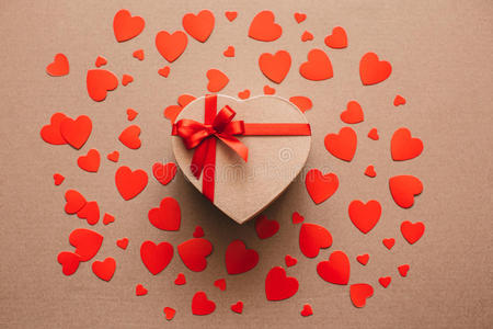 礼品盒包装在再生纸上，红色丝带蝴蝶结在红心的背景上。