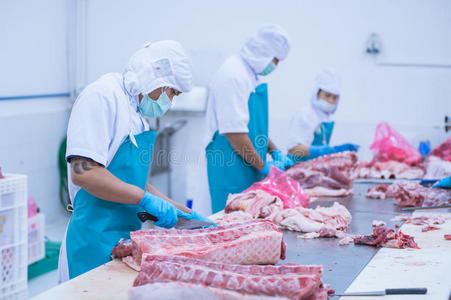 在工厂里切肉屠宰场的工人照片