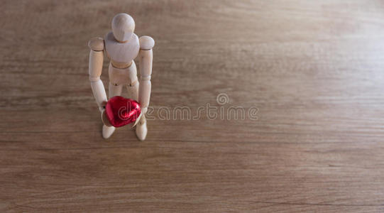 一个木娃娃男人在情人节在木地板上表现出爱和关系的行为。