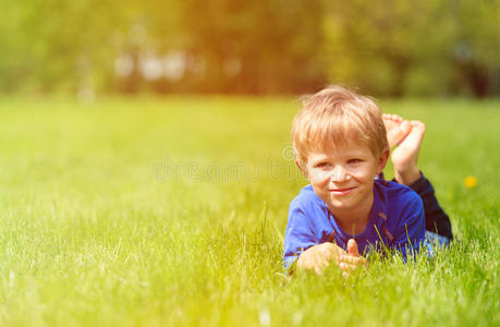 可爱快乐的小男孩躺在春天的青草里