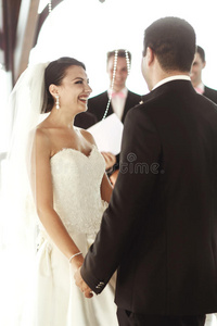 穿着白色连衣裙的美丽新娘和英俊的新郎在婚礼上交换戒指