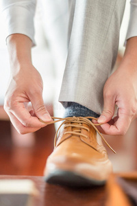 商人或新郎把鞋带系在他的棕色鞋子上。