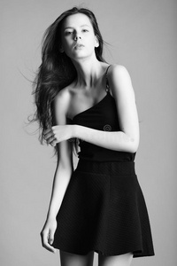 美丽的年轻模特穿着优雅的黑色连衣裙在工作室摆出不同的情绪。