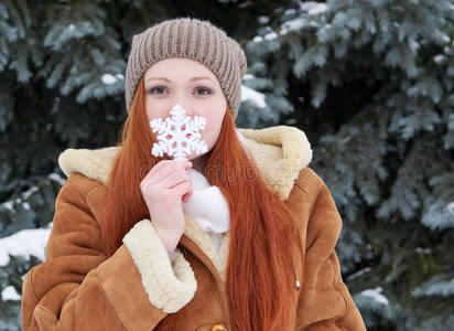 冬天森林里的女孩肖像，下雪的天气，展示大雪花玩具。