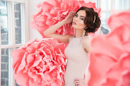 漂亮的女孩穿着一件长裙，窗前坐着一朵巨大的粉红色的花