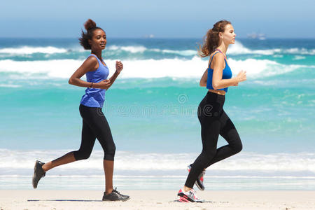 两位适合在海滩上跑步的年轻女性的全长肖像