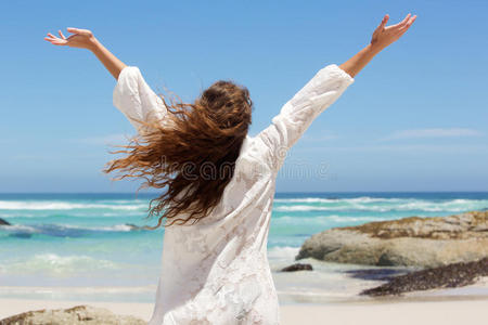 在海边举起手臂的模型的背面照片