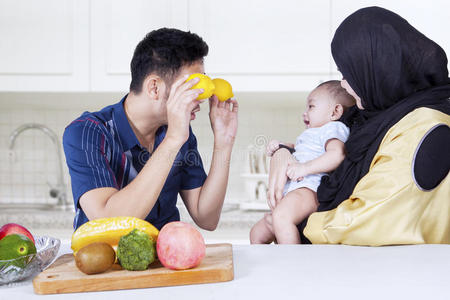 父亲在厨房和婴儿玩水果