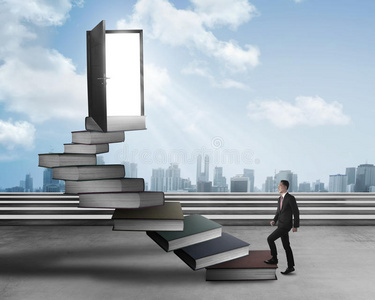 亚洲商人从书本上爬上楼梯照片