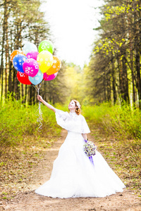 欢快的新娘带着一堆气球在户外